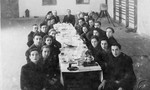 Students in their last year of a high school in Marijampole sit around a table set with glasses.