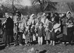 Group portrait of refugees in Croatia standing outside a wooden farmhouse.