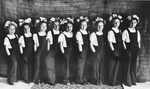 Young girls, dressed in overalls and with flowers in their hair, put on a school performance at the Novaky labor camp.
