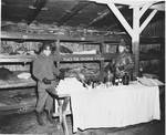 An American soldier looks at items on a display table inside a barracks in the Buchenwald concentration camp.