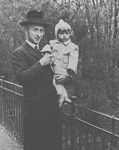 An Orthodox Jewish man poses with his small child in his arms.