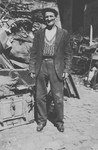 A Deaf and mute Jewish man poses in front of a pile of discarded scrap metal.