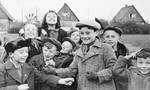 A large group of children stands in humorous poses for a photograph in the Neu Freimann displaced person's camp.