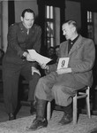 An American military lawyer presents a document to defendant Johann Kick during the Dachau war crimes trial.