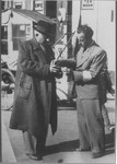Pao Chia member with an armband examining the pass of a Jewish refugee.