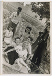 A group of young people wearing Stars of David picnic in a field outside the Lodz ghetto.