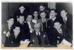 Teenagers, holding their diplomas, pose together with Mordechai Chaim Rumkowski (seated in the middle front) during their high school graduation excercise.