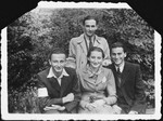 Four young people, one of whom is wearing an armband, pose together in the Krakow ghetto.