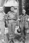 Portrait of three American soldiers standing in front of a building.
