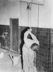 A prisoner reenacts a torture pose in the prison of the Dachau concentration camp.