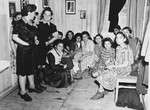 A large group of women gather in a room with curtains after the liberation of the Dachau concentration camp.