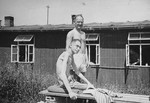 Two emaciated survivors of the Buchenwald concentration camp pose outside the hospital barracks.