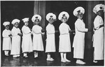 Eight Jewish children wearing Purim costumes stand in a line.