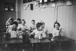 Young Dutch-Jewish children brought from the creche to a children's home by the Dutch underground sit at their desks.