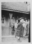American soldiers enter a barrack in the Buchenwald concentration camp while a survivor smiles in the foreground.