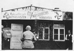 An American serviceman looks at an anti-Nazi banner hanging outside a barrack in the Buchenwald concentration camp.