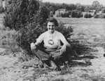 A Jewish teenage girl poses next to a shrub in the Polish countryside.