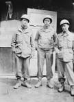 Three American soldiers from the 6th Armored Division pose in front of a building in the Buchenwald concentration camp.