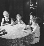 Four Jewish children sit around a table and play a card game in their apartment in Geneva, Switzerland.