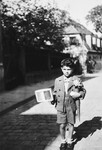 A Jewish-Czech boy poses with a cone and book on his first day of school.