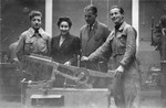 Four people pose by a piece of machinery in what probably is a vocational training school in a displaced persons' camp in Switzerland.