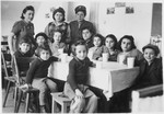 Children sit around a table set with glasses in either the Foehrenwald or the Windsheim displaced persons' camp.