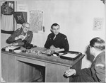 Henry Cohen, the UNRRA director of the Foehrenwald displaced persons' camp, meets with two other officers in his office.