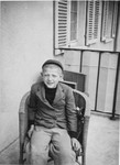 Close up portrait of a Jewish boy siting on a porch chair in the Windsheim displaced persons' camp.