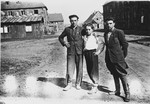Three men pose together on a street of the Windsheim displaced persons' camp.