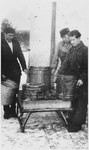 Three men lift large barrels in what [probably is the Windsheim] displaced persons' camp.