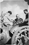 Dr. Curt Bondy assists poses with two students next to a tractor at the Gross Breesen agricultural training center.