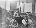 A young Jewish girl attending a vocational training in the Gross Breesen agricultural center cuts and cleans rhubarb while sitting outside.