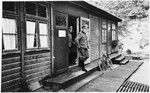 Commandant Hermann Pister exits a wooden building (possibly an administrative barracks)  at Hinzert (a sub-camp of Buchenwald).