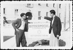 Two men pose next to a sign outside the Bindermichl displaced persons' camp in Linz, Austria.