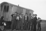 A group of Roma poses alongside a caravan, possibly during a wedding.