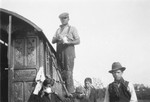 A Romani man standing on a ladder works on his caravan.