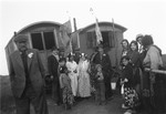 A Romani wedding party poses in front of two caravans.