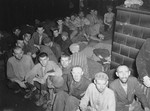 Survivors sit on the floor of a crowded barrack in the Dachau concentration camp.