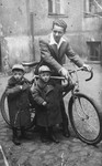 A young Polish-Jewish father stands next to his bicycle and his twin sons.