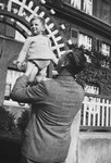 A German-Jewish father lifts his young son high in the air.