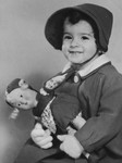 Studio portrait of a young Jewish child holding her doll, taken about a year before she perished in Auschwitz

Pictured is Suzanne Hochherr.