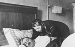 A German-Jewish wife leans over her sleeping husband.