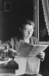 A German-Jewish woman sits in her home and reads the newspaper.
