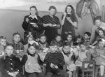 Group portrait of Jewish kindergarten children sitting around a table for a celebration in Lodz after the war.