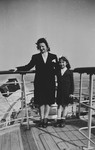 A mother and daughter pose on the top deck of a ship [while on route to the United States].