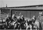 Several Russian political prisoners sit by a fence after the liberation of Buchenwald.