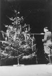 SS officer Karl Hoecker lights a candle on a Christmas tree only weeks before the liberation of Auschwitz.