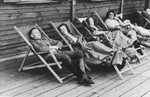 SS officer Karl Hoecker relaxes with women in lounge chairs on the deck of the retreat in Solahuette.