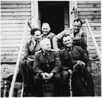 Five SS officers sit on the outside steps to a wooden building in Gross-Rosen.