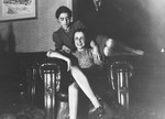 Two German-Jewish women pose together on a large leather armchair.